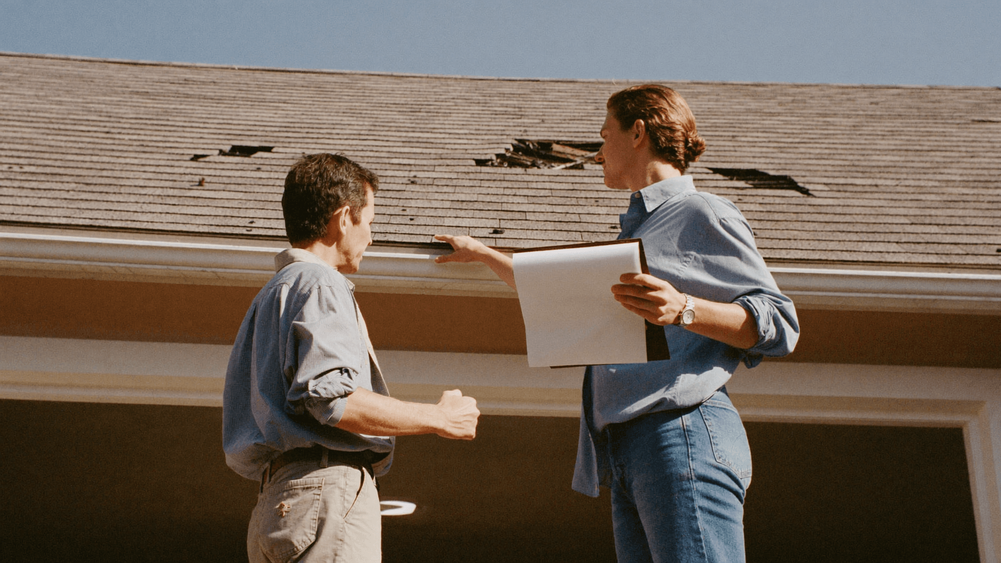 Homeowner and roofing inspector reviewing storm damage in the driveway