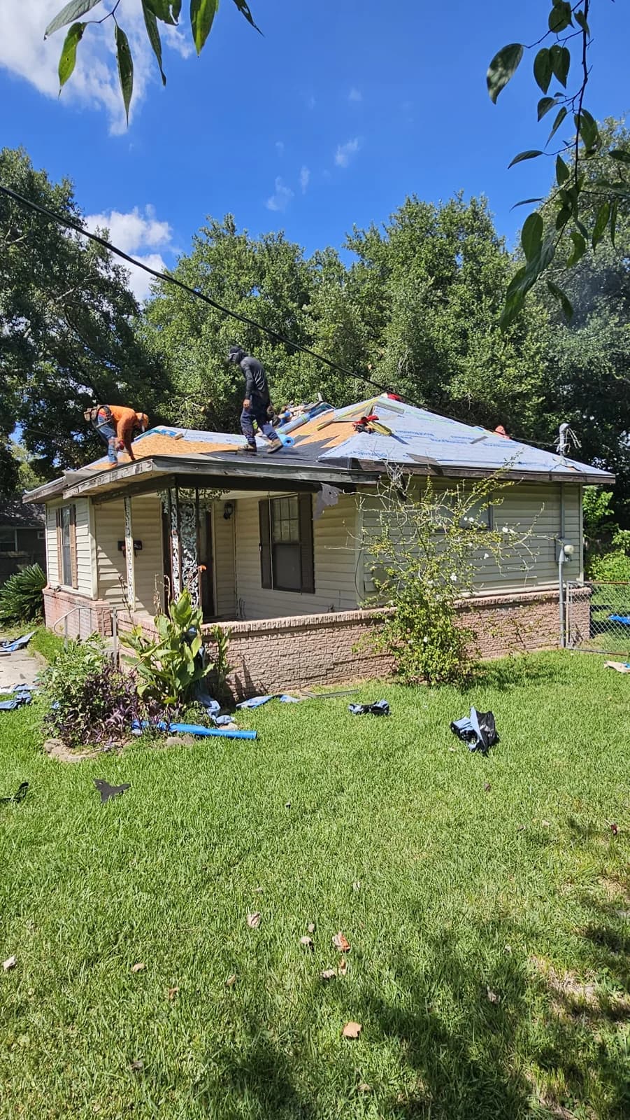 Roofing crew working on the Baytown home with exposed decking and roof underlayment visible